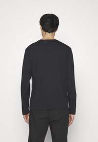 Langsleeve shirt in zwarte katoen, ronde hals, effen kleur, minimalistisch ontwerp, soepele textuur, met lange mouwen en een ontspannen pasvorm.