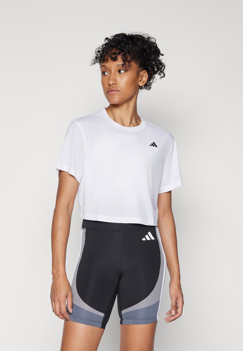 Hvit kortermet t-skjorte med svart logo, kombinert med svarte shorts med grå paneler og hvite detaljer. Jevnt stoff, atletisk passform.