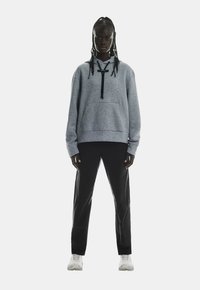 Grau Fleece-Hoodie mit Kordelzug und Kängurutasche, kombiniert mit schwarzen Hosen und weißen Sneakern, vor einem schlichten weißen Hintergrund gezeigt.