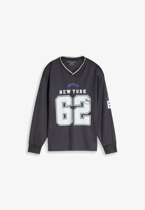 Zwart oversized overhemd met lange mouwen en V-hals, witte "New York 62" tekst en blauwe en witte details op de voorkant en mouw.