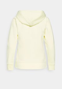Un sweat à capuche jaune avec une texture douce, une grande capuche et des poignets côtelés. Il présente un design simple sans embellissements ni motifs.