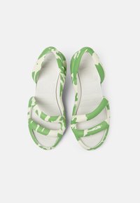 Green and white camo-patterned sandals with a smooth, flexible rubber material; feature wide cross straps and textured footbed.