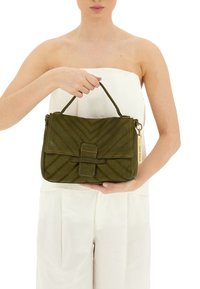 Borsa a tracolla verde oliva realizzata in materiale testurizzato, caratterizzata da un design a zig-zag, una chiusura a pattina e un manico corto. Dettagli in hardware color oro.