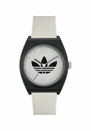 Melnas taisnstūra formas pulkstenis ar baltu silikona siksniņu. Sudraba ciparnīca ar melnu logotipu, stundu marķieriem pie 12 un 6, kā arī minimālistisku dizainu.