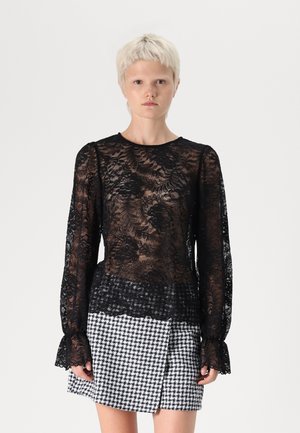 Black lace top with floral pattern, long sleeves, and ruffled cuffs, paired with a black-and-white houndstooth mini skirt.