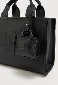 Μαύρη δερμάτινη τσάντα DKNY με υφή και τσάντα mini που ταιριάζει, προσαρτημένη στη λαβή, με ανάγλυφο λογότυπο εμφανές και στις δύο τσάντες.