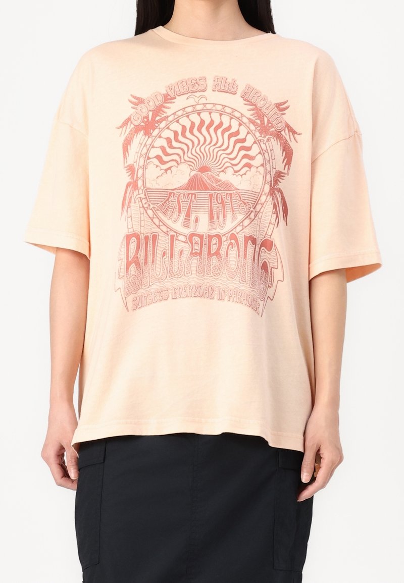 Camiseta oversized de color rosa claro, hecha de algodón suave, que presenta un diseño gráfico con palmeras y elementos de estallido solar en un tono rojo contrastante.