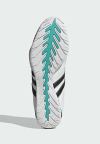 Biela atletická podrážka so čiernymi pruhmi, s textúrovaným vzorom dezénu a akcentom v tyrkysovej farbe pozdĺž stredu pre lepšiu trakciu.
