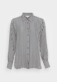 Camisa de botão em padrão vichy preto e branco, com mangas longas, gola clássica e um corte solto; apresenta botões escuros e um tecido texturizado.