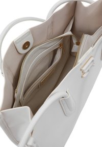 Borsa in pelle bianca con accessori in oro, dotata di più tasche interne e di un compartimento con zip. Texture liscia con un design strutturato.