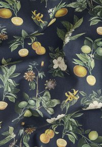 Blomstret stof med gule og grønne citrusfrugter, hvide blomster og grønne blade på en mørk marineblå baggrund; blød tekstur.