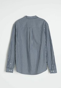 Koszula z długim rękawem w granatowe i białe pionowe paski, z wykończeniem przy plecach, zapiętymi mankietami i luźnym krojem. Tekstura z bawełny.