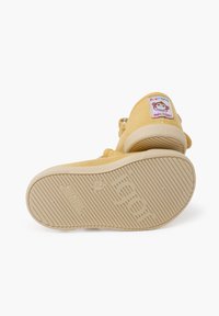Scarpa di tela gialla con suola in gomma testurizzata, dotata di un patch con logo di scimmia e una cinghia regolabile per una vestibilità sicura.