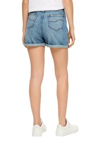 Jasnoniebieskie szorty dżinsowe z postrzępionym dołem. Posiadają dwie tylne kieszenie z zaokrąglonym przeszyciem. Noszone z białymi trampkami.