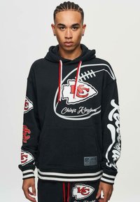 Black hoodie with red accents and white graphic designs, featuring team logos and "Chiefs Kingdom" text. Cotton blend, kangaroo pocket, striped hem.