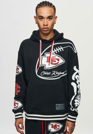 Black hoodie with red accents and white graphic designs, featuring team logos and "Chiefs Kingdom" text. Cotton blend, kangaroo pocket, striped hem.