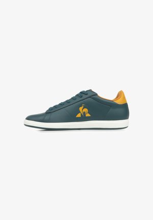 Sneaker in pelle color teal con suola bianca, dettagli arancioni e cuciture. Presenta il logo sul lato e un classico design con lacci.