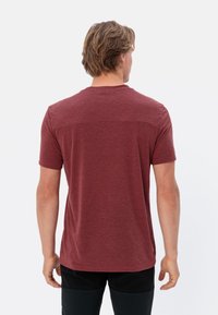 Bordeaux kortekolen T-shirt van een zachte, gestructureerde stof. Ronde halslijn, rechte snit. Label zichtbaar aan de onderlinkerkant.