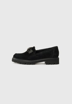Mocassins en daim noirs avec un bout arrondi, ornés de deux pierres noires décoratives sur le devant et d'une semelle en caoutchouc noir robuste.