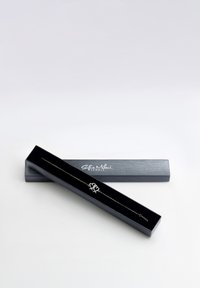 Bracciale in argento con un ciondolo a forma di cuore, presentato in una elegante scatola nera con branding argentato, caratterizzato da un design di catena delicato.