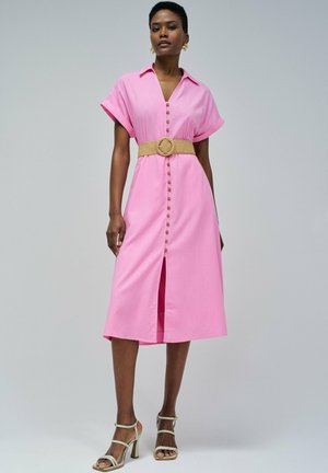 Rosa Button-Down-Kleid mit kurzen Ärmeln, tailliert durch einen beigen Gürtel und einem Schlitz vorne, kombiniert mit beigen Riemchen-Heels.