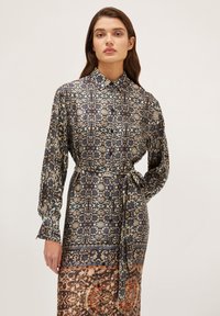 Rochie cu mânecă lungă dintr-un material mătăsos, având un model floral în nuanțe de albastru, bej și brun, cu guler și un cordon legat la talie.