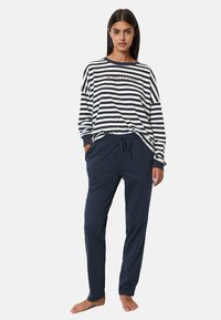Gestreepte langharige top in marineblauw en wit, met logo detail, gecombineerd met marineblauwe broek met trekkoord met een relaxte pasvorm en een gladde textuur.