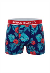 Shorts boxer bleu marine avec un motif floral vibrant comprenant des hibiscus rouges et des feuilles turquoise, soulignés par une ceinture rouge portant l'inscription « SERGE BLANCO ».