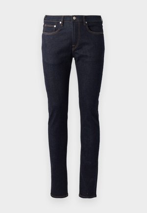 Jeans en denim bleu foncé avec une coupe slim, un design à cinq poches, des coutures contrastantes orange et une fermeture à bouton.
