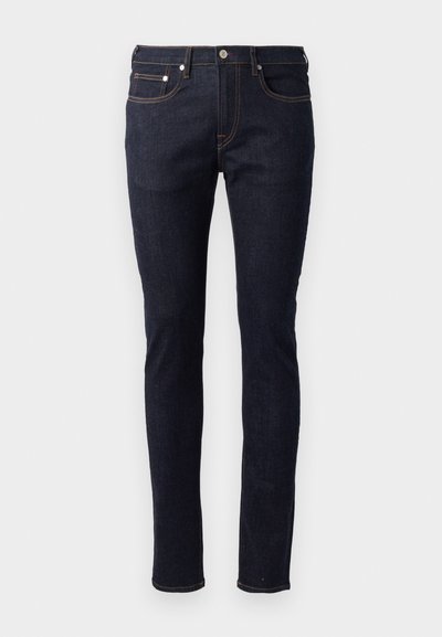 Jeans en denim bleu foncé avec une coupe slim, un design à cinq poches, des coutures contrastantes orange et une fermeture à bouton.