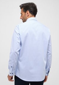 Camicia a righe blu chiaro con maniche lunghe, polsini con bottoni e colletto classico, caratterizzata da una texture di tessuto liscia e una vestibilità su misura.