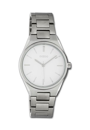 Montre en acier inoxydable argenté avec un cadran rond blanc, des index horaires minimalistes et un bracelet en métal composé de petites maillons rectangulaires.