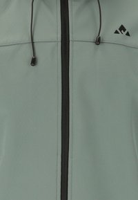 Vaaleanvihreä vetoketjullinen takki, jossa musta vetoketju ja kiristysnyörit, yläoikealla pieni musta kolmion muotoinen logo.