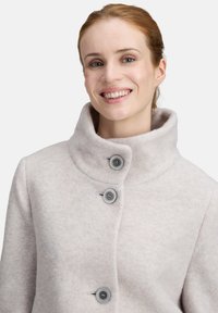 Fleecejacke in Hellgrau mit einem hohen Kragen, drei grauen Knöpfen an der Vorderseite und einer glatten Textur. Einfaches und funktionales Design.