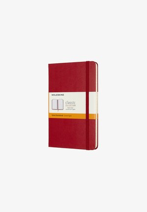 Quaderno Moleskine rigido a righe di colore rosso, con chiusura elastica e un'etichetta visibile che dettaglia la Classic Collection. Superficie testurizzata.