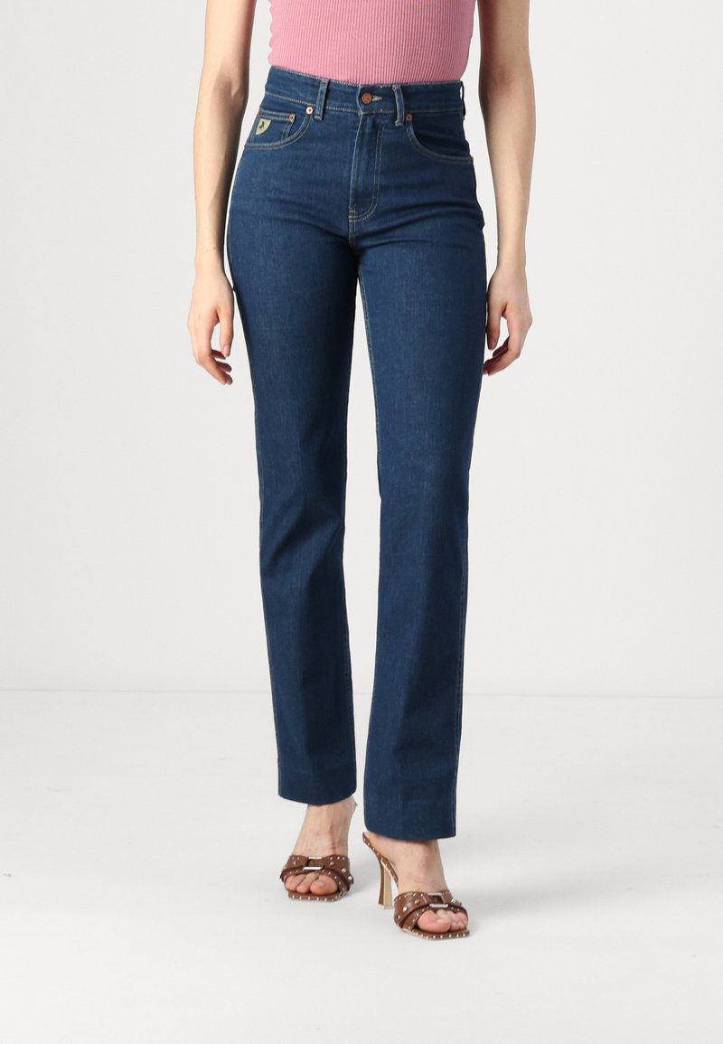 Dark blue high-waisted jeans feature a straight leg design, five pockets, gold stitching, and a branded patch on the back.
