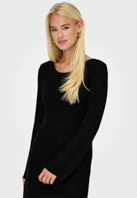 Robe noire en tricot à manches longues avec un col rond. Le tissu a une finition texturée, et les manches ont une légère évasement au poignet.