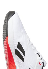 White athletic shoe with black stripes, textured upper, red and turquoise accents on the sole, and a padded tongue with white laces.