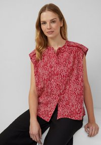 Rode blouse met patroon en korte mouwen, voorzien van een ruit- en geometrisch print, knoopsluiting en een losse pasvorm, gecombineerd met zwarte broek.