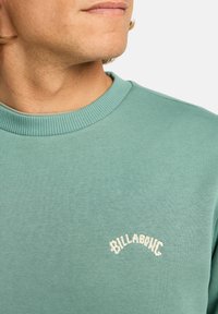 Felpa verde menta realizzata in morbido tessuto, con collo a costine e logo "Billabong" ricamato in bianco sul petto.