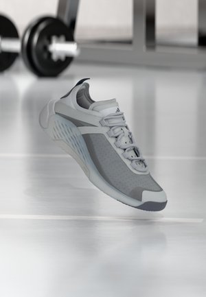 Lysegrå sportssko med mesh- og gummimaterialer, indeholder perforerede områder, en polstret sål og et struktureret greb bagpå.