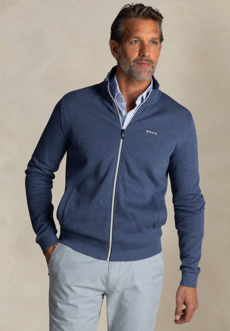Navyblauwe zip-up trui van zachte stof met geribde mouwen en onderkant, met een klein logo op de linkerborst en zijzakken.