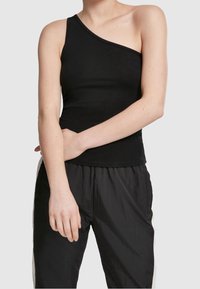 Débardeur noir avec un décolleté asymétrique, fabriqué en tissu extensible, design ajusté, texture lisse et ourlet soigné. Associé avec un pantalon noir.