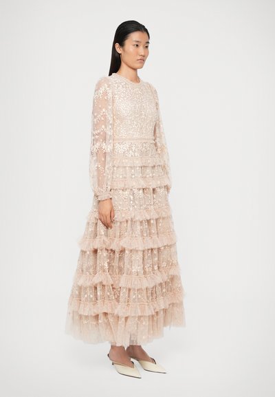 Sluoksniuota, kelių lygių suknelė iš skaidraus, lengvo audinio švelniai rožinės spalvos, su gėlių siuvinėjimu ir ilgomis, apimtinėmis rankovėmis.