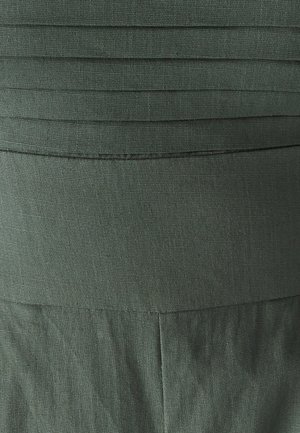 Tissu vert foncé avec une texture plissée en haut, finition lisse en bas. Présente un design simple sans matériel ou motifs visibles.