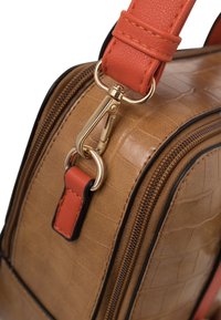 Sac en cuir texturé couleur fauve avec fermoir en métal doré et attache de sangle en cuir orange près d'une fermeture éclair.