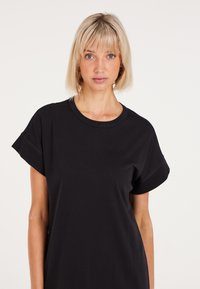 Schwarzes T-Shirt mit kurzen Ärmeln aus weichem Stoff, mit Rundhalsausschnitt und lockerer Passform. Schlichtes Design ohne sichtbare Muster oder Akzente.