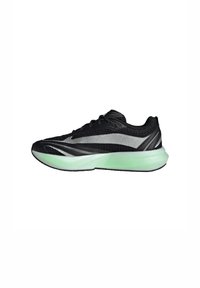 Scarpa sportiva nera con una tomaia testurizzata, dettagli riflettenti argento e una suola verde traslucida. Design elegante e aerodinamico con lacci.