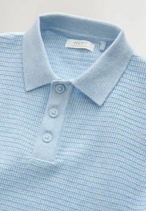 Svetlo modra pletena polo majica z teksturirano tkanino, tremi gumbi v isti barvi in klasičnim ovratnikom. Oznaka na notranji strani navaja "NEXT".