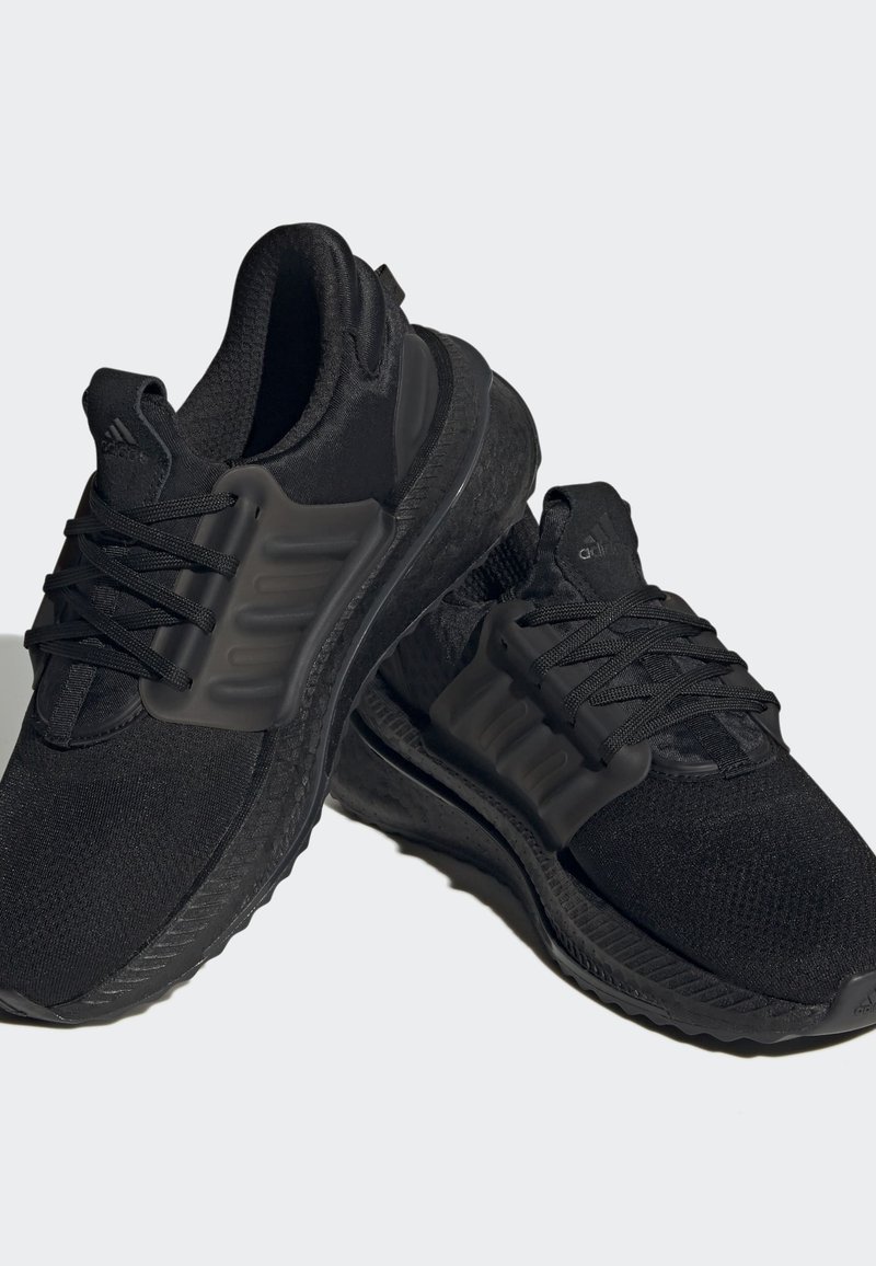 Schwarze Sportschuhe mit einem Mesh-Obermaterial und Gummisohle, ausgestattet mit einem auffälligen seitlichen Stützelement und strukturierten Akzenten auf der Sohle.